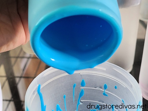 Blue paint in a candle being poured into a cup.