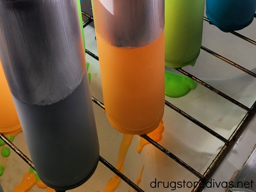 Painted candles drying on a wire rack.