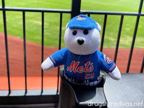 A polar bear stuffed animal in a Mets hat and jersey above a baseball field.