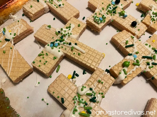 Cross-shaped wafer cookies with white chocolate and green sprinkles.