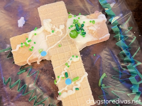 A cross-shaped wafer cookies with white chocolate and green sprinkles.