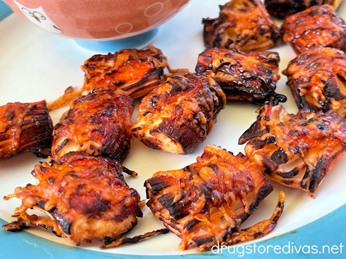 Spicy air fryer imitation crab bites on a white and blue plate with a pink and blue bowl in the back.