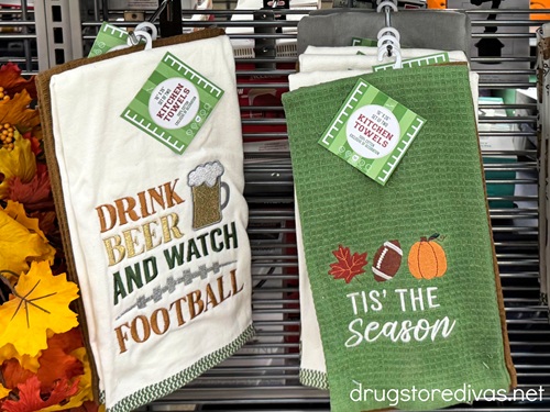 Two football themed kitchen towels hanging on pegs in a store.