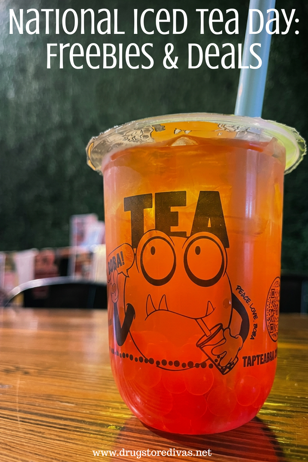 A boba tea drink in a plastic cup with a monster on it on a table with the words 
