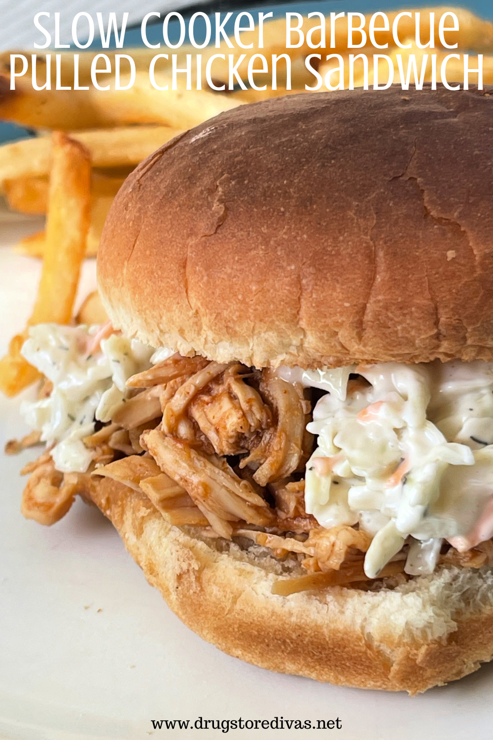 A pulled chicken sandwich topped with coleslaw with fries in the back and the words 