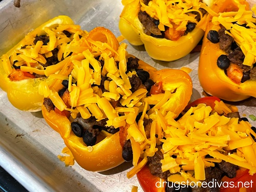 Stuffed pepper halves with shredded cheese on top on a silver tray.