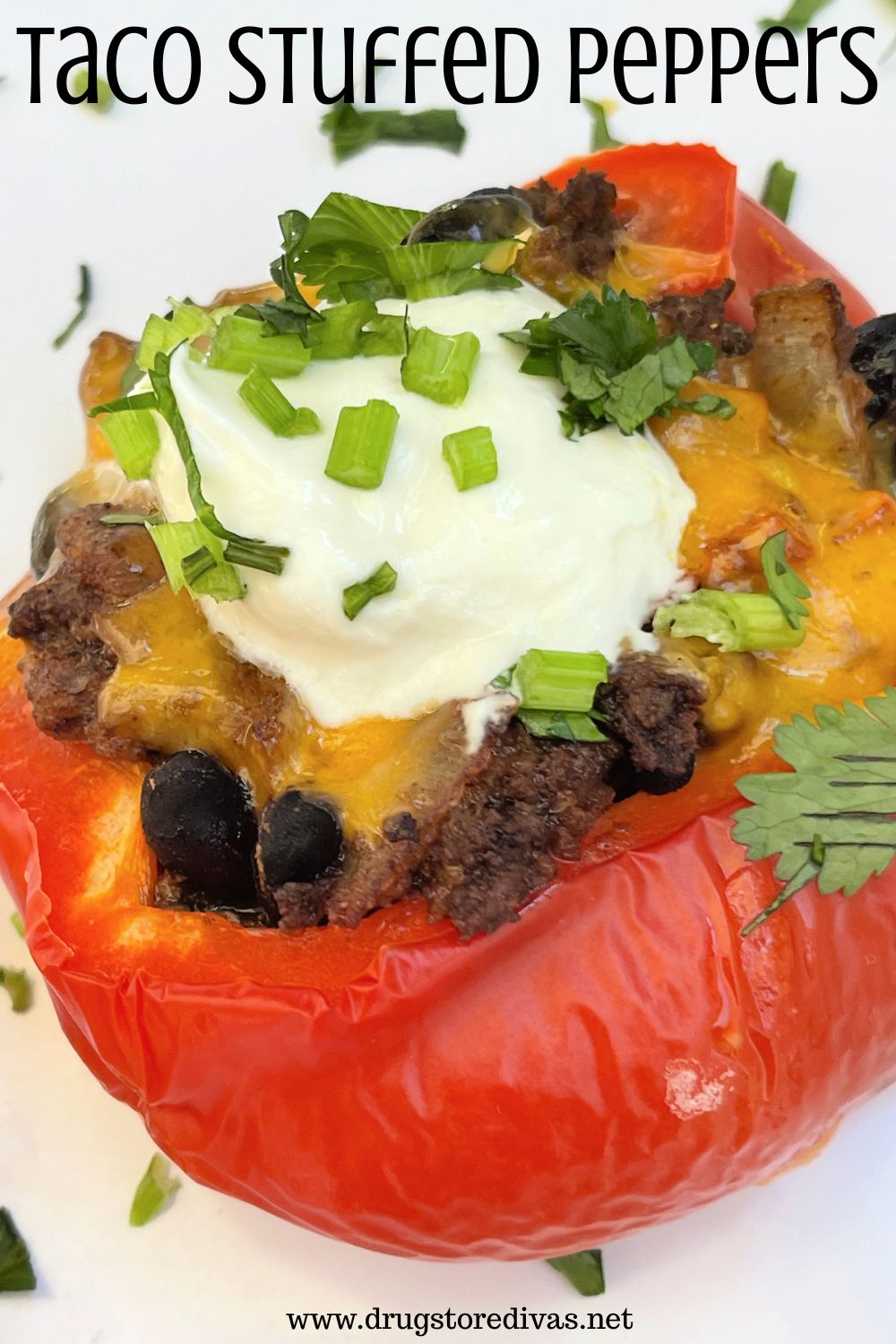 A red stuffed pepper with melted cheese, sour cream, and green herbs on top with the words 