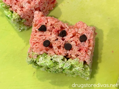 Two watermelon rice krispies treats on a green cutting board.