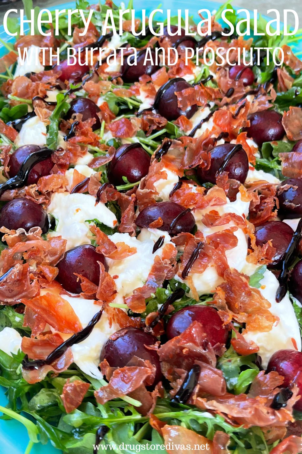 Arugula, topped with cherries, burrata, and crispy meat with a drizzle on top and the words 