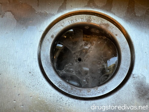 A garbage disposal in a sink with bubbles coming out of it.