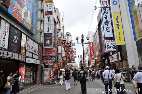 People walking through Dotonbori Japan with stores and restaurants on each side of them.