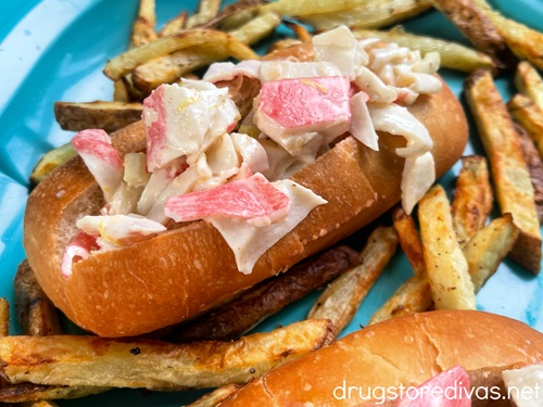 A crab roll and homemade French fries on a blue tray.