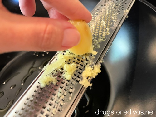 Fingers grating ginger on a microplane.