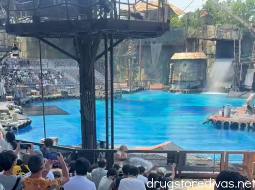 An audience watching a pool of water during the WaterWorld show at Universal Studios Japan.