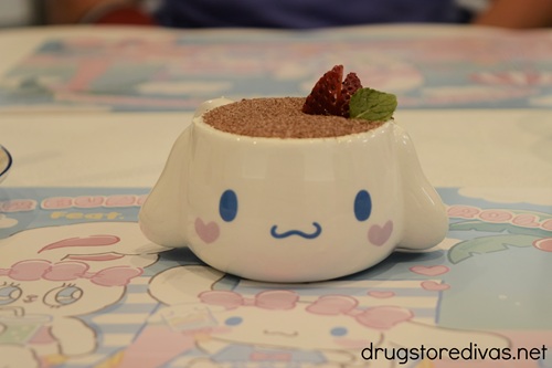 A cup shaped like Cinnamoroll's face with chocolate cake in it and strawberry pieces coming out the top.