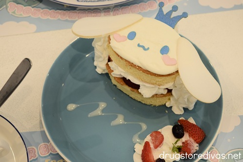 A cake shaped like Cinnamoroll's face on a blue plate.
