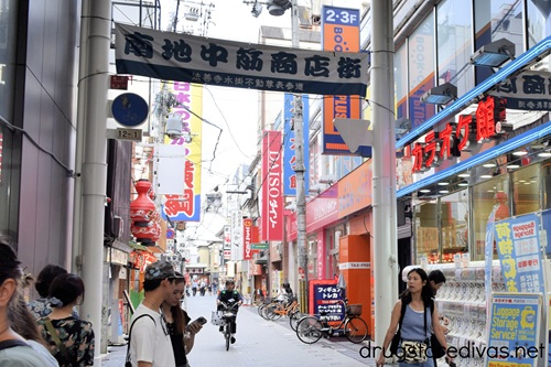 The outside of a shopping street in Namba, Japan with a Daiso store sign on the side.