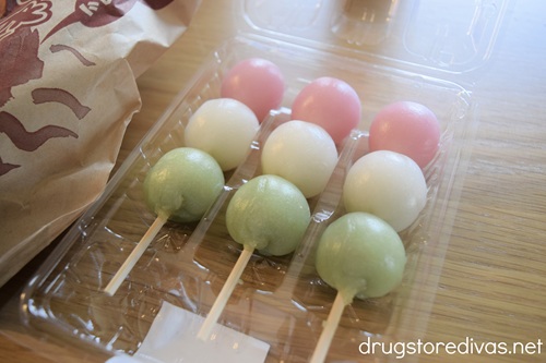 Three pieces of Hanami Dango on skewers in a box on a table.