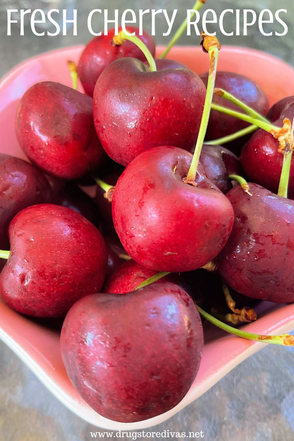 A pink bowl filled with fresh cherries and the words 