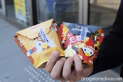 A man's hand holding two packages of Lawson's chicken nuggets, known as karaage, in Japan.