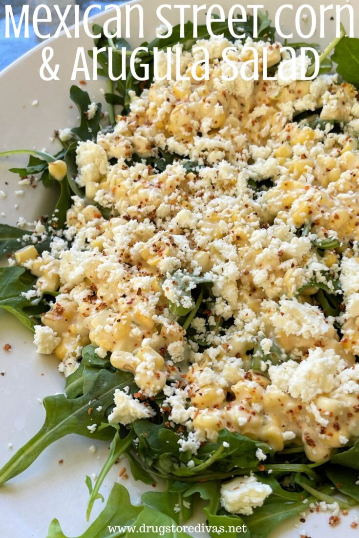 Corn and white crumbled cheese on top of arugula with the words 