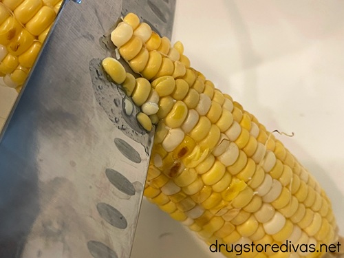 A knife cutting kernels off a corn cob.