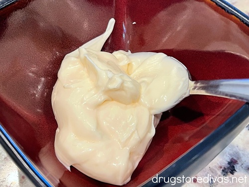 Mayonnaise and  spoon in a maroon bowl.