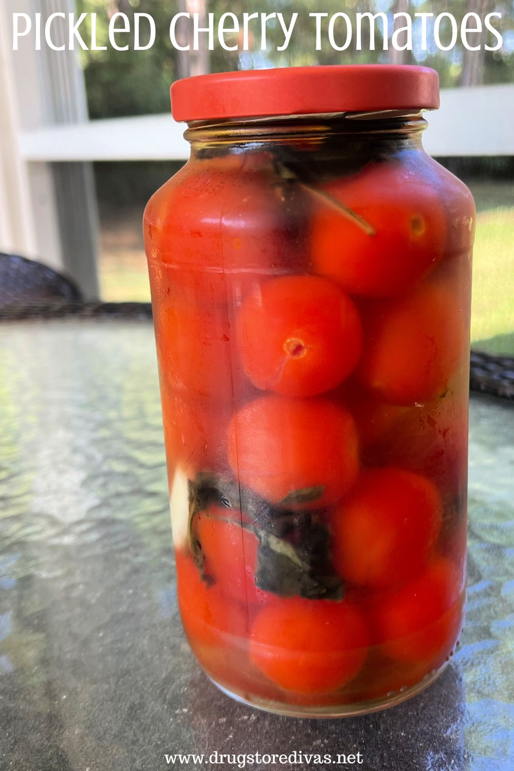 A glass jar with a red to with tomatoes and basil inside on a glass table with the words 