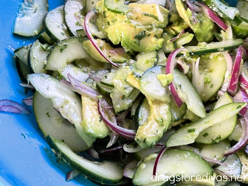 Cucumber, avocado, and red onion in a blue bowl.