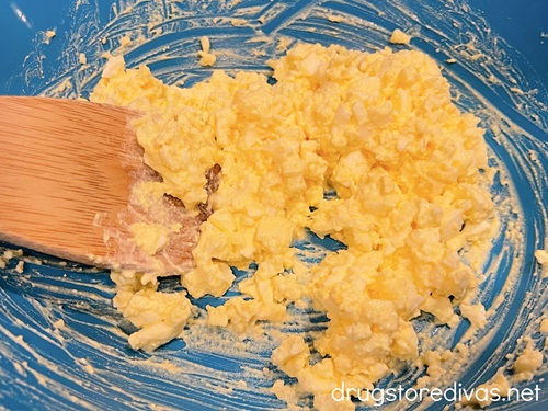A creamy egg mixture and a bamboo spoon in a blue bowl.