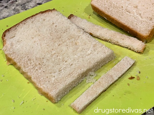 White bread with the crust cut off on a lime green cutting board.