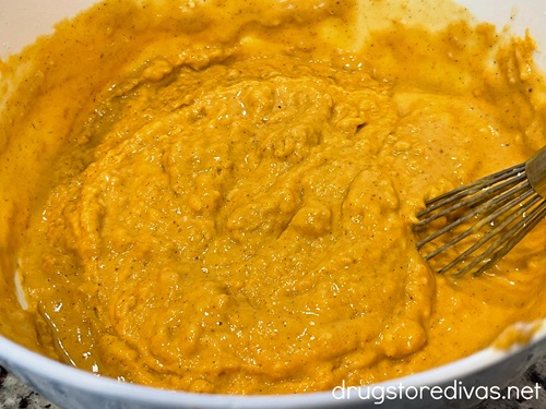 An orange batter in a white bowl with a whisk in it.