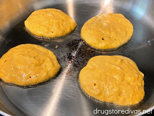 Four pancakes in a silver skillet.