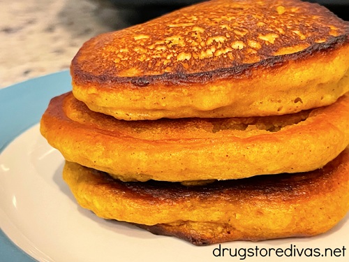 Three pumpkin pancakes on a white and blue plate.