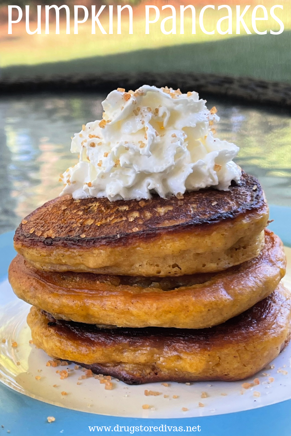 Three pancakes stacked on top of each other on a blue and white plate with whipped cream on top and sugar over it with the words 